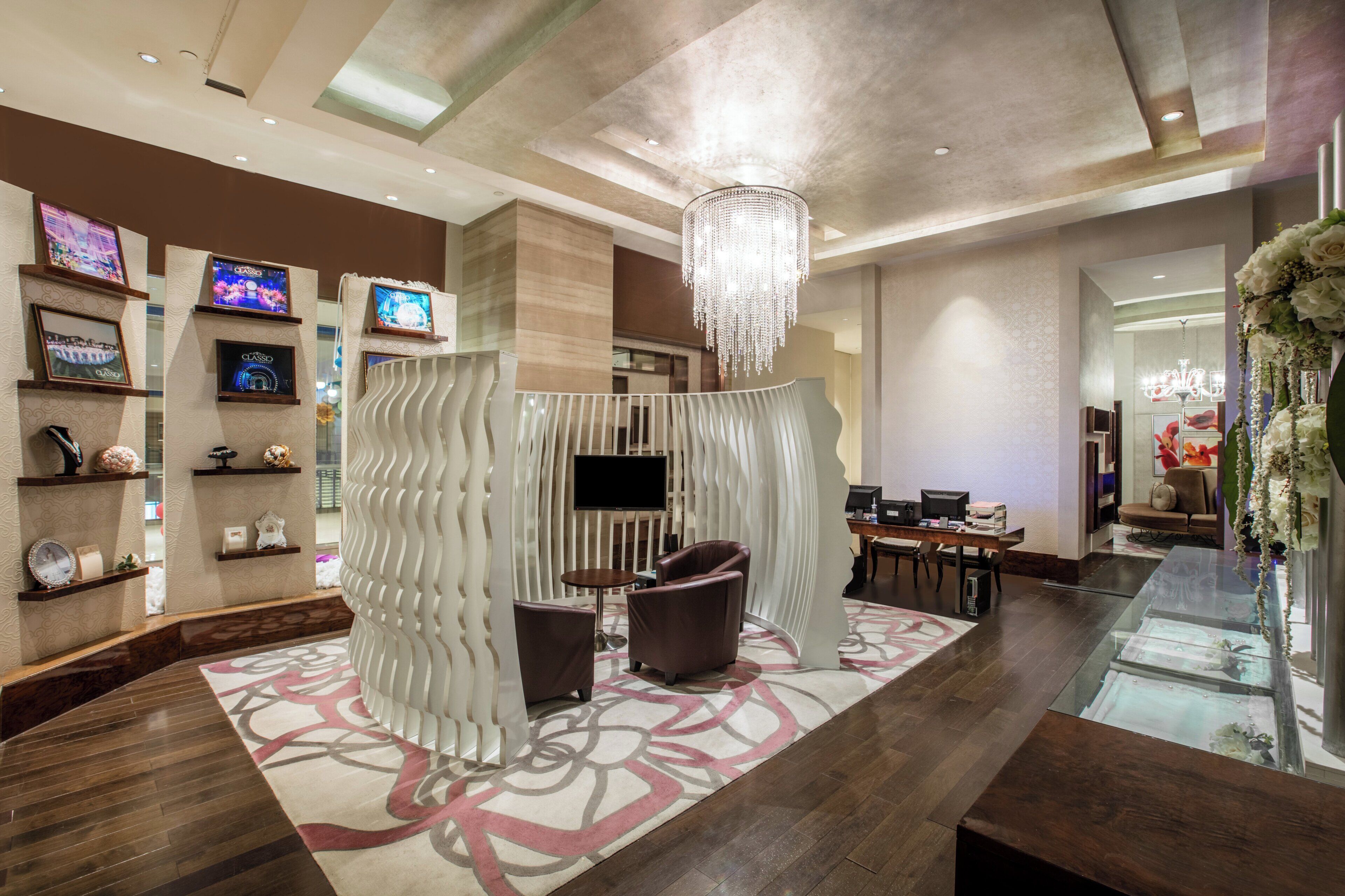 A modern lobby with a seating area, a chandelier, and a TV mounted on the wall.