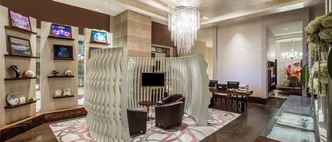 A modern lobby with a seating area, a chandelier, and a TV mounted on the wall.