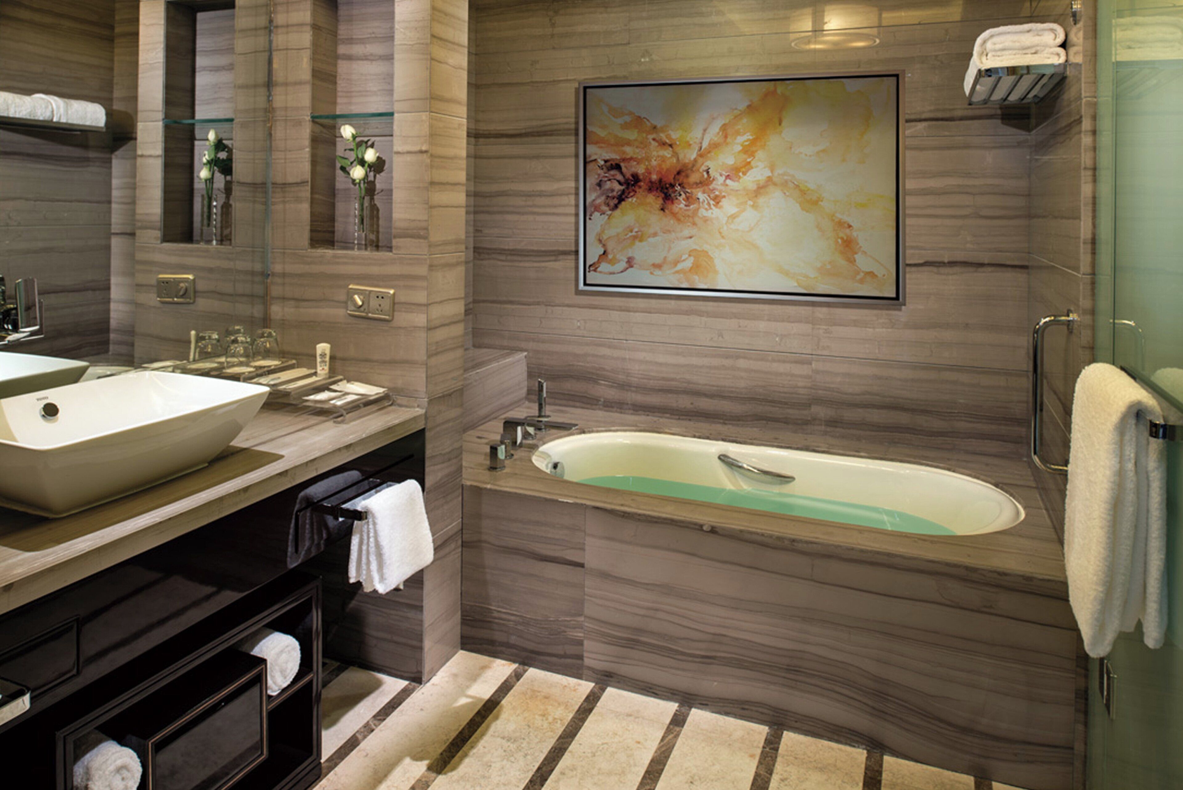 A modern bathroom with a large sink, a bathtub, and a glass shower enclosure.