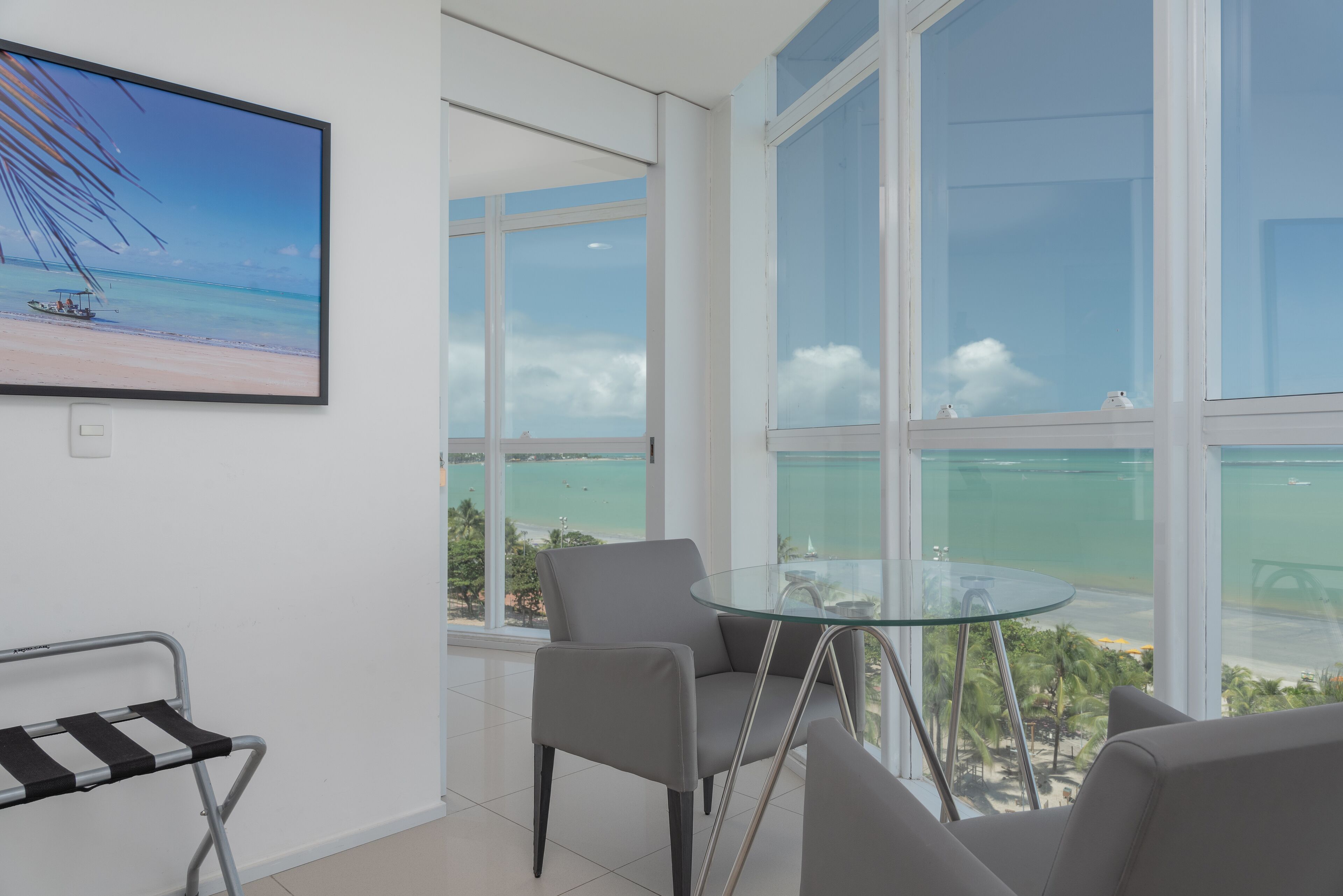 A modern room with a large window offering a view of the beach and ocean.