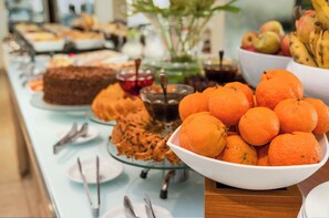 A buffet table with various food items including oranges, cakes, and fruits. - Hotel Brisa Praia (Maceió)