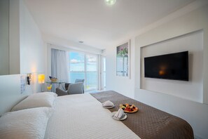 A hotel room with a large bed, a TV, a desk with a chair, a window with a view of the sea, and a breakfast tray on the bed. - Hotel Brisa Praia (Maceió)