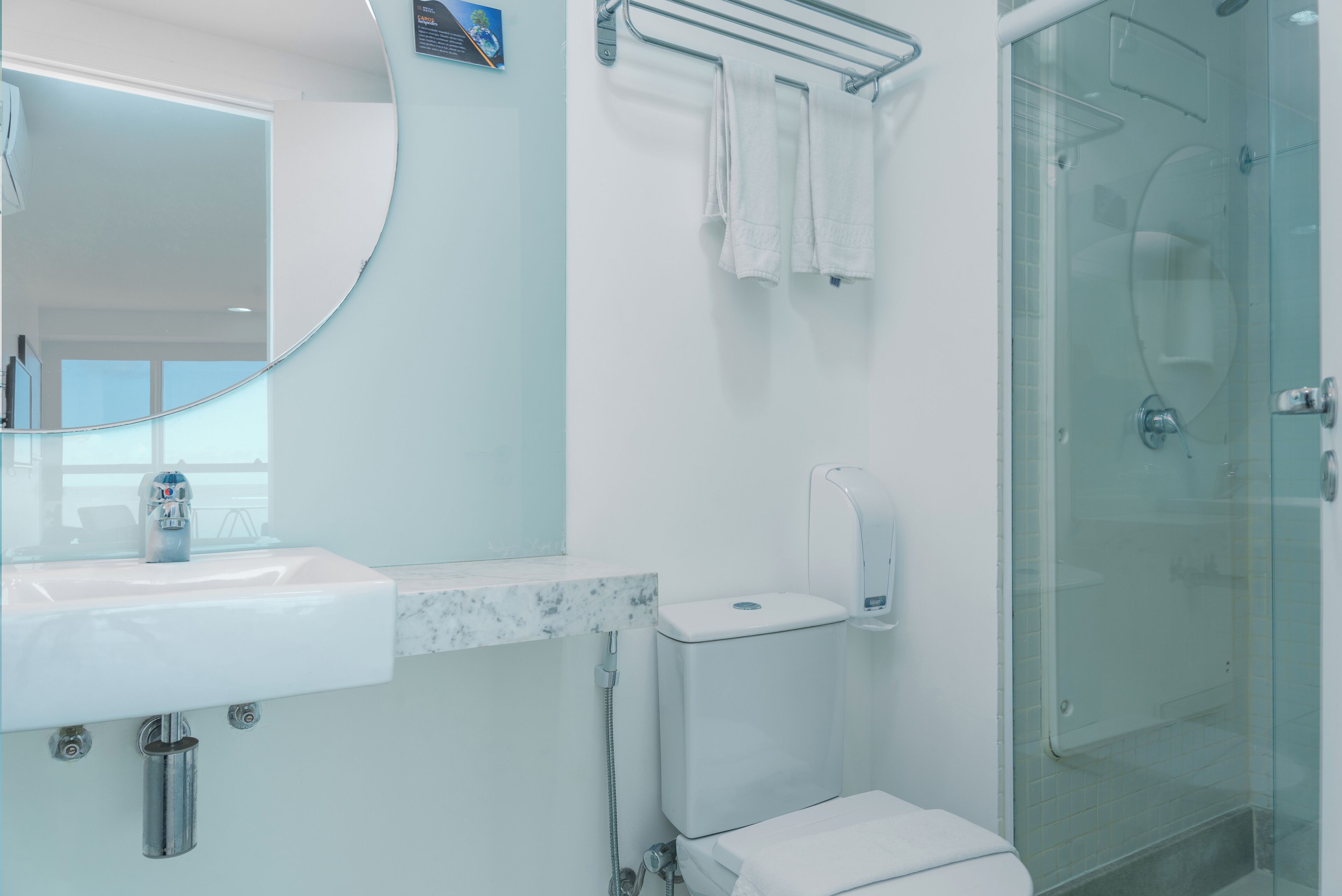 A modern bathroom with a sink, toilet, and glass shower enclosure.