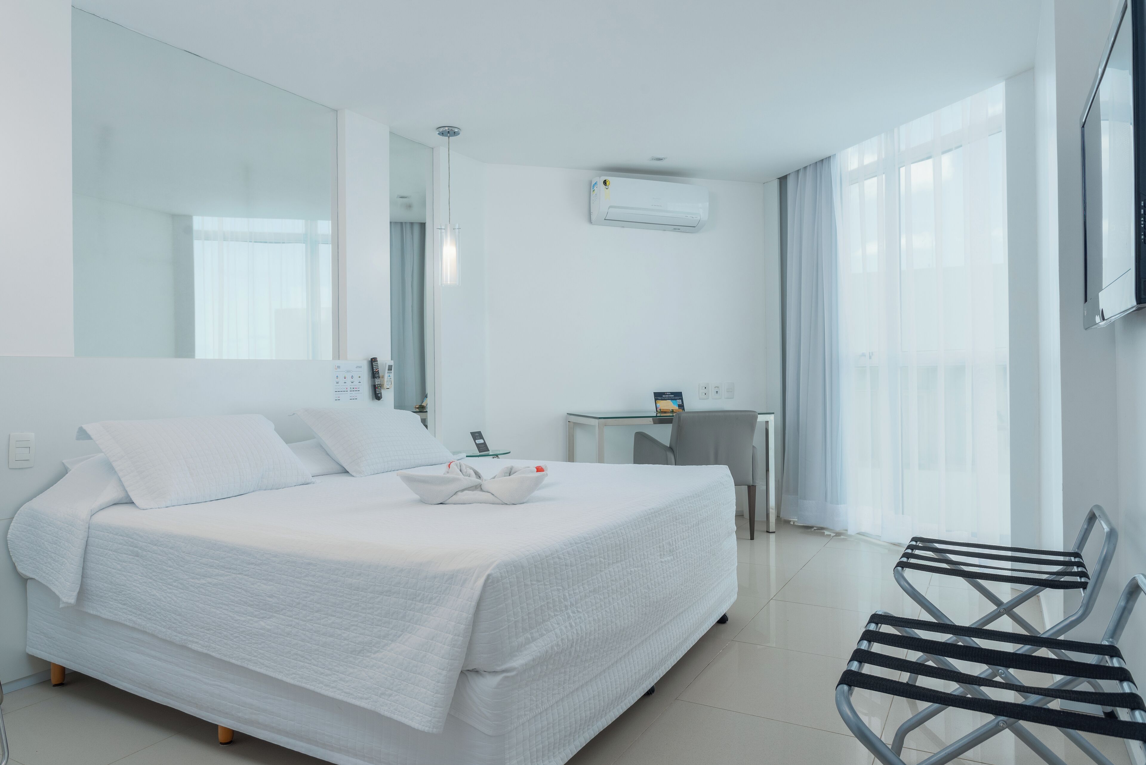 Una habitación de hotel con una cama grande, un escritorio, una silla y un televisor.