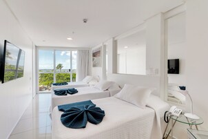 Habitación de hotel con dos camas, un ventanal con vistas, un televisor de pantalla plana y un teléfono.