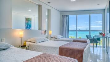 Habitación de hotel con dos camas, un escritorio y vista al océano.