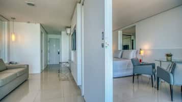Uma sala de estar moderna e bem iluminada, com um sofá, uma área de jantar com mesa e cadeiras, e um espelho grande na parede.