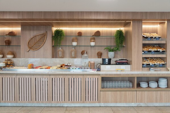 A buffet area with wooden paneling, glass shelves displaying food items, and a variety of kitchen appliances.