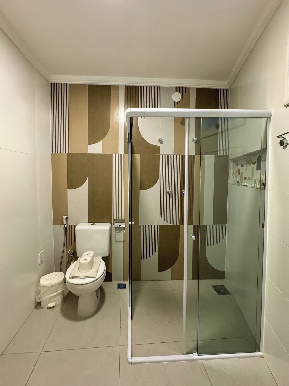 Een badkamer met toilet, bidet en een douchecabine met glazen wanden.