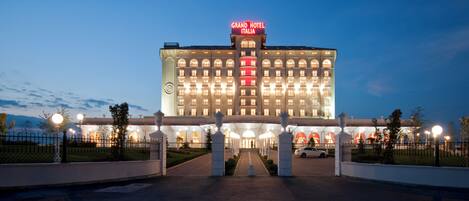 Un hotel grande con un cartel llamativo que dice "Grand Hotel Italia" en la parte superior.