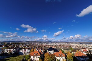 Vista panorámica de un paisaje urbano con edificios residenciales, cielo despejado y montañas a lo lejos.