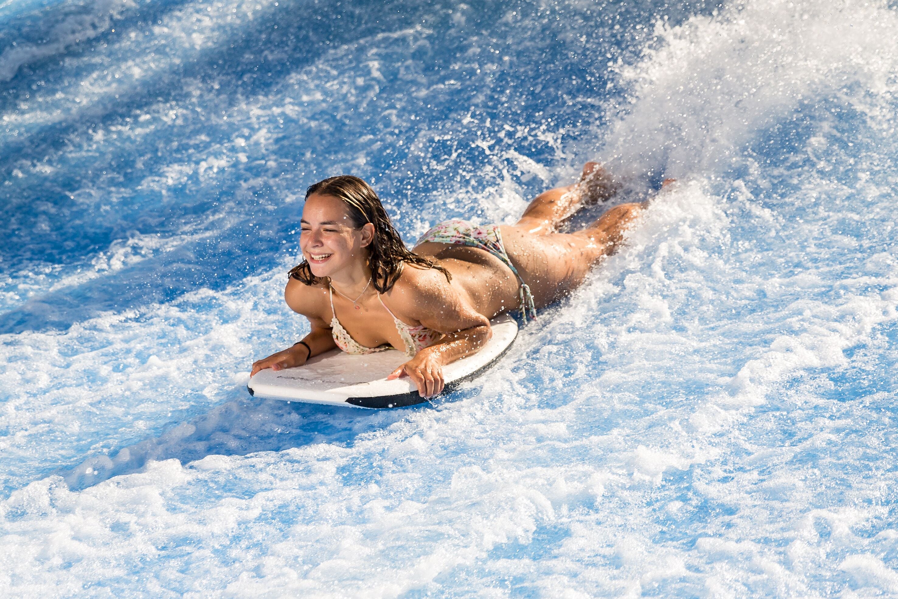A person lying on a surfboard in a water body.