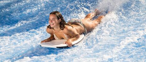 A person lying on a surfboard in a water body.