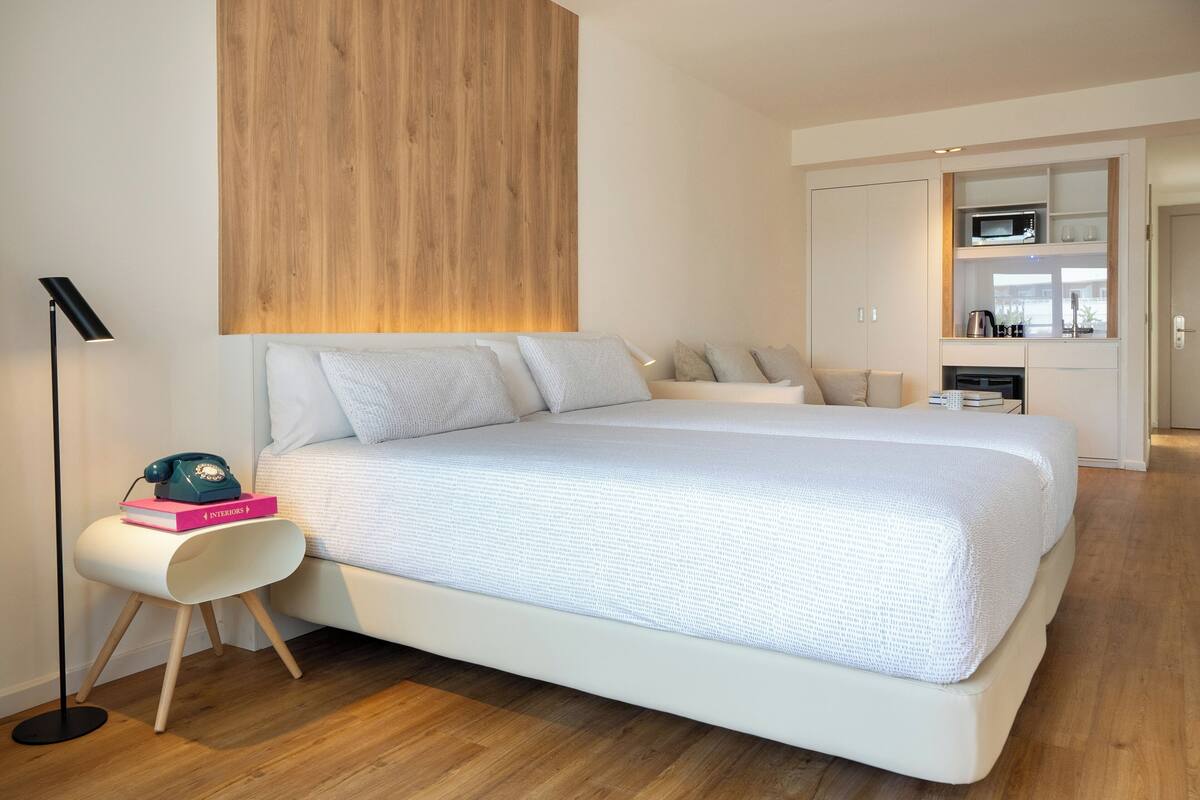Un dormitorio moderno con una cama grande, una mesita de noche con lámpara y una pared de madera decorativa.