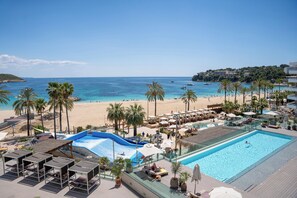 Una piscina al aire libre, sombrillas, sillones reclinables de piscina