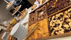 Un bufé con diversas opciones de panadería, incluyendo pasteles, brownies y tartas.