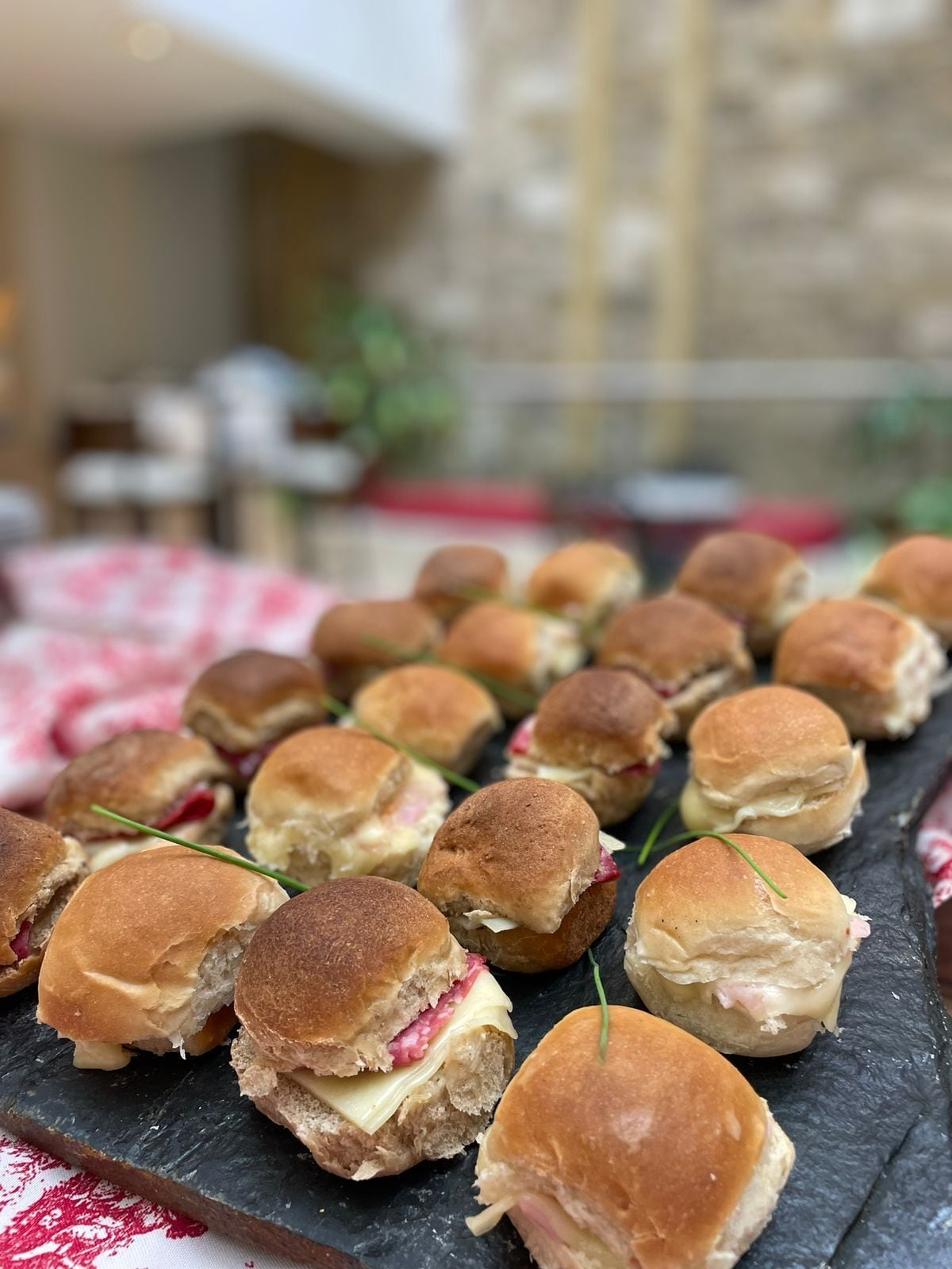 Una pizarra con mini sándwiches, algunos con rellenos a la vista.