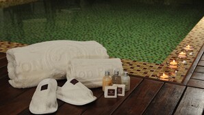 A wooden deck with a towel, slippers, and candles near a pool. - Kenton Palace Buenos Aires (Buenos Aires)