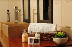 Un tocador de baño con una toalla, botellas y una planta en maceta.