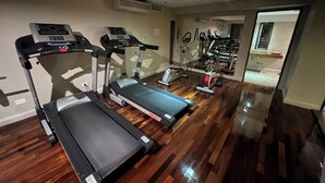 Gimnasio en casa con cintas de correr, elípticas y un espejo que refleja el espacio de ejercicio.