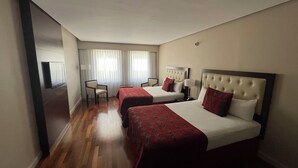 Una habitación de hotel con dos camas, un escritorio, una silla y un televisor.