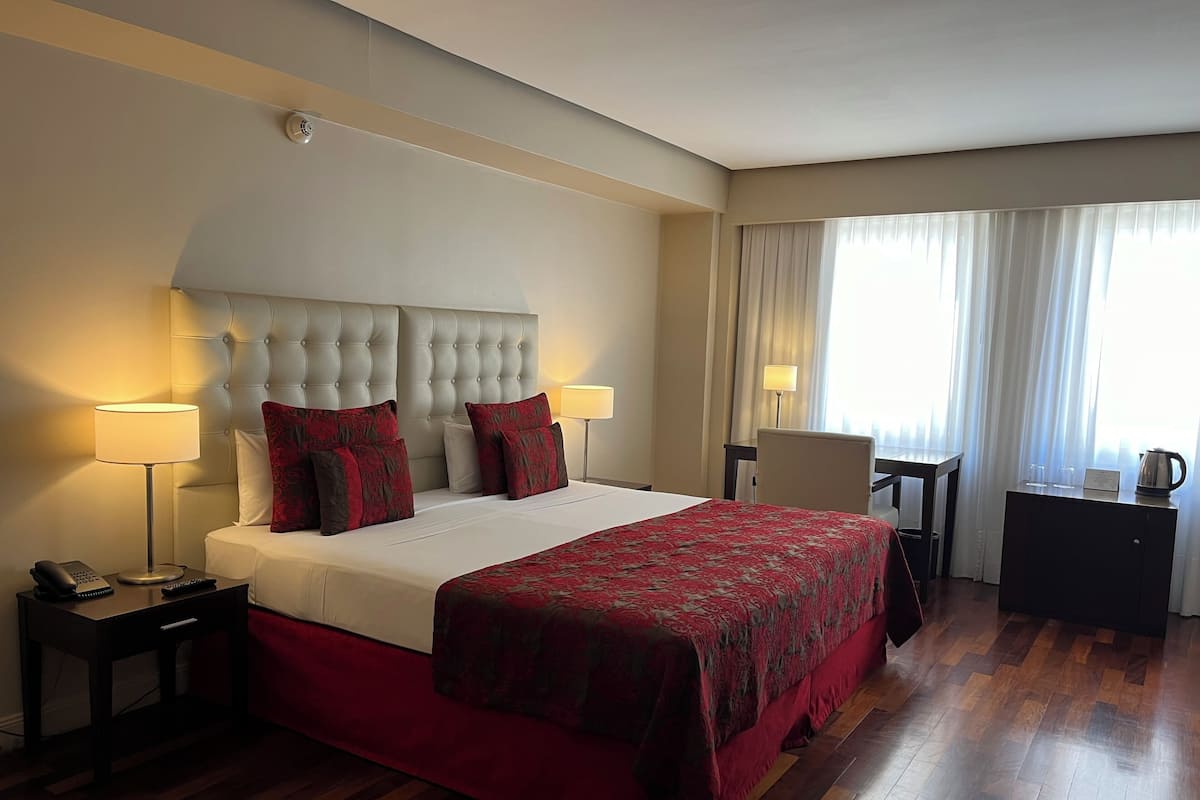 Una habitación de hotel con una cama grande, dos lámparas de noche, un escritorio y una silla.