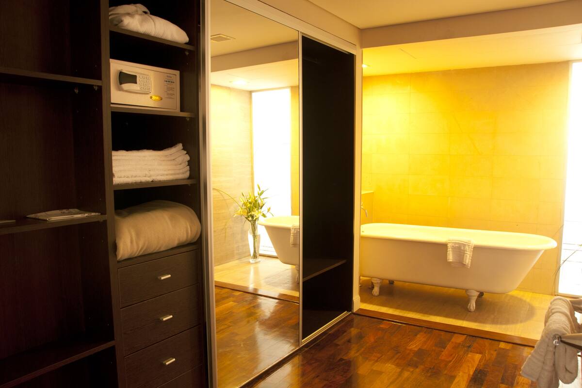Un baño moderno con una bañera independiente, suelo de madera y un mueble de tocador empotrado con espejo.