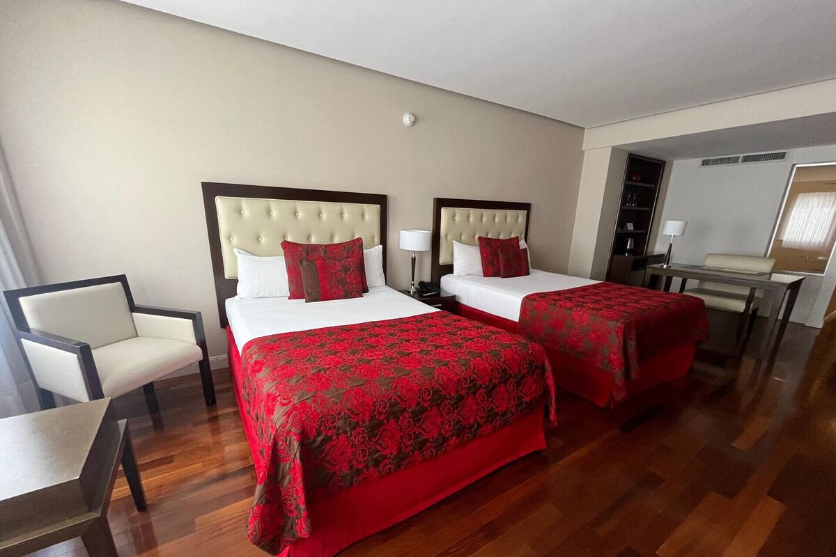 Habitación de hotel con dos camas, una silla, un escritorio y un espejo.