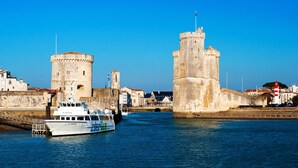 A coastal cityscape with historic towers and a boat named "la maine" on the water. - Lagrange Apart'HOTEL L'Escale Marine (La Rochelle)