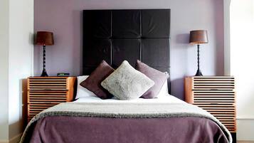 A neatly arranged bedroom with a large bed, two bedside tables, and a headboard.
