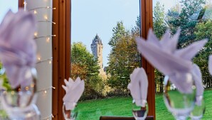 Une table à manger avec vue sur une tour, visible à travers une fenêtre.