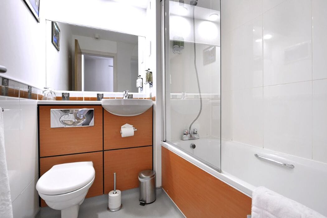 Un baño moderno con inodoro, lavamanos y ducha.