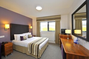 A hotel room with a bed, bedside lamps, a desk with a computer, and a large mirror. - Stirling Court Hotel (Stirling)
