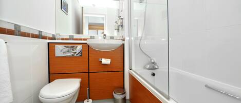 Un baño moderno con inodoro, lavamanos y ducha envuelta en vidrio.