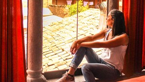A person sitting on a bed in a room with a view through an archway. - Fuente de Agua Cusco Hotel (Cusco)