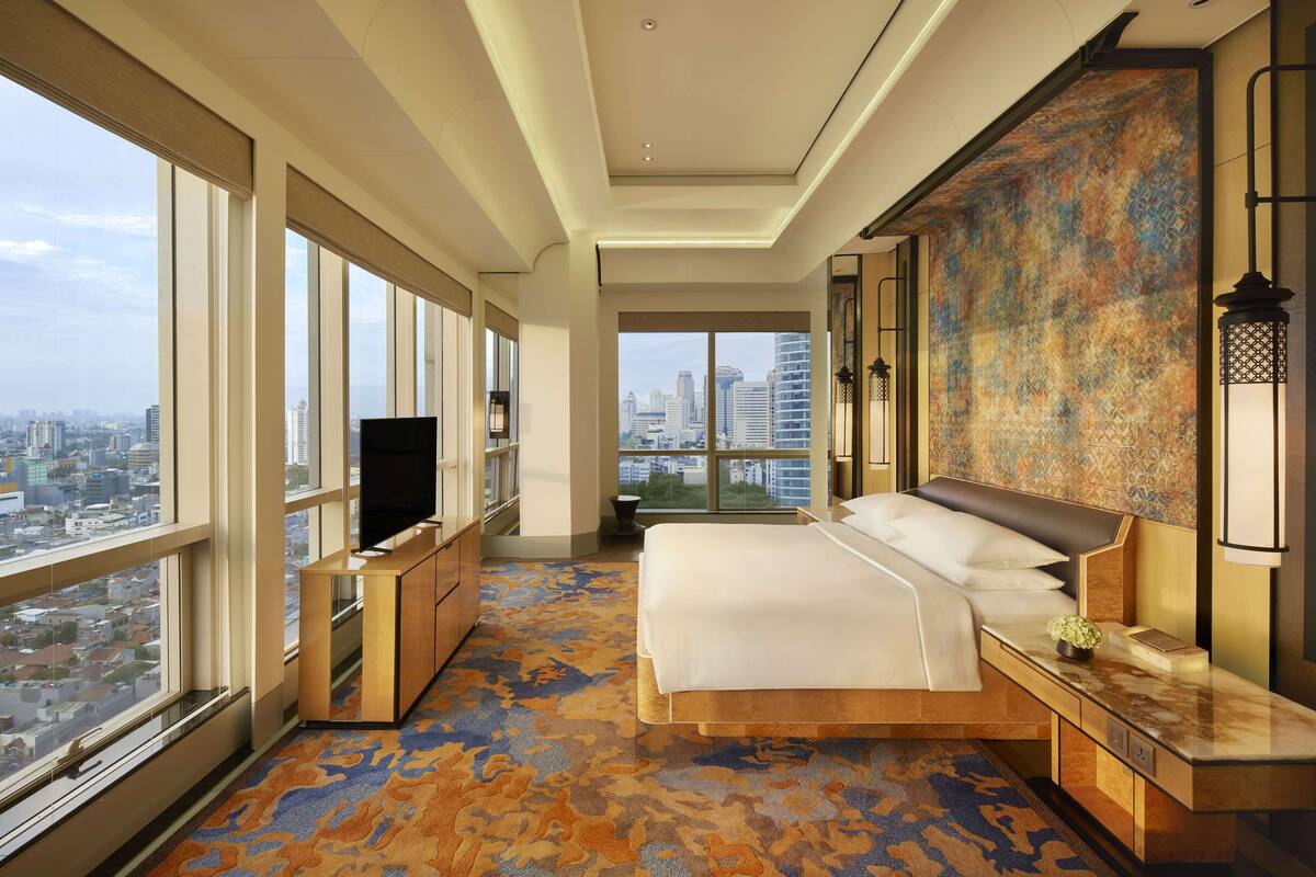 Ein modernes Hotelzimmer mit einem großen Bett, einem Fernseher und Blick auf die Stadt.