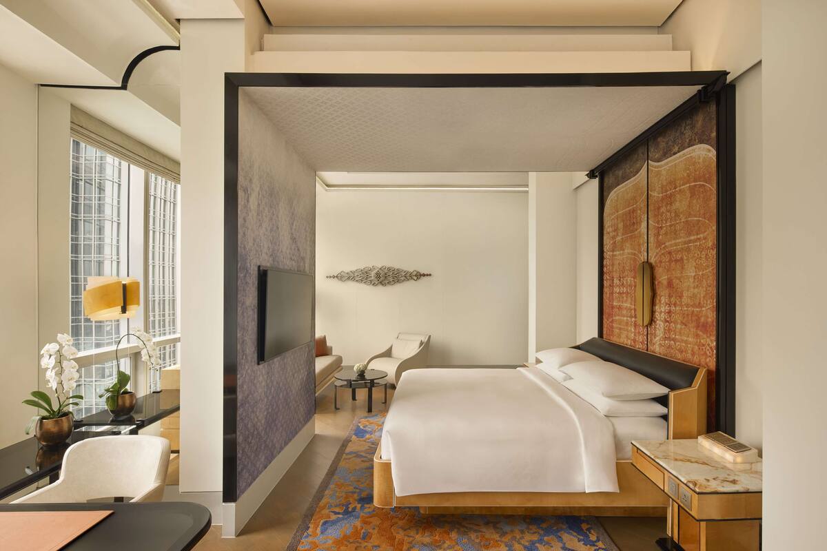 Ein modernes Hotelzimmer mit einem großen Bett, einem Schreibtisch, einem Stuhl, einem Fernseher und Blick auf die Stadt.