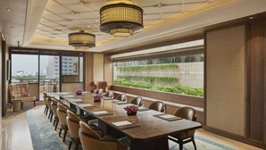 A modern conference room with a long table, comfortable chairs, and large windows offering a view of greenery and buildings. - Keraton at The Plaza, The Unbound Collection by Hyatt (Jakarta)
