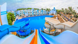 Un resort con una piscina grande, varias toboganes acuáticos y una hilera de villas con balcones.