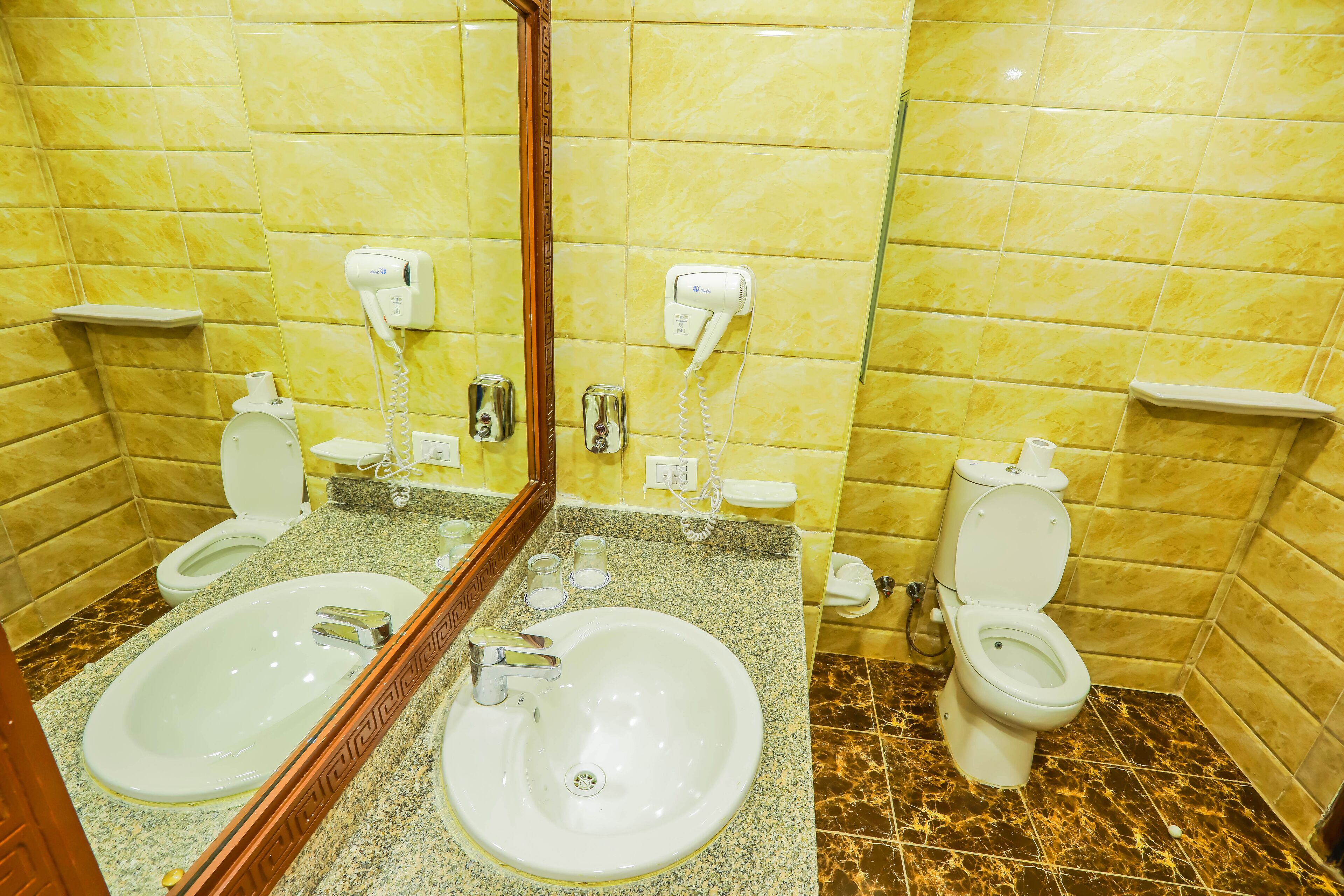 Un baño con dos lavamanos, un espejo y un inodoro.