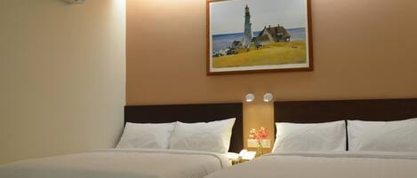 Habitación de hotel con dos camas, un cuadro de un faro y una mesita de noche con una lámpara.