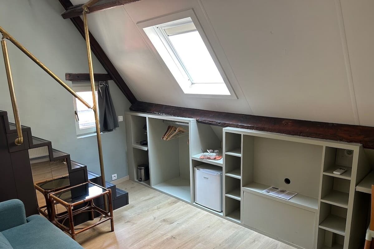 Um quarto estilo loft com um claraboia, uma área de jantar com mesa de vidro e estantes embutidas.