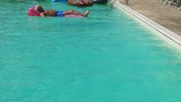 Una piscina al aire libre, sillones reclinables de piscina