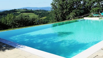 Una piscina al aire libre, sillones reclinables de piscina