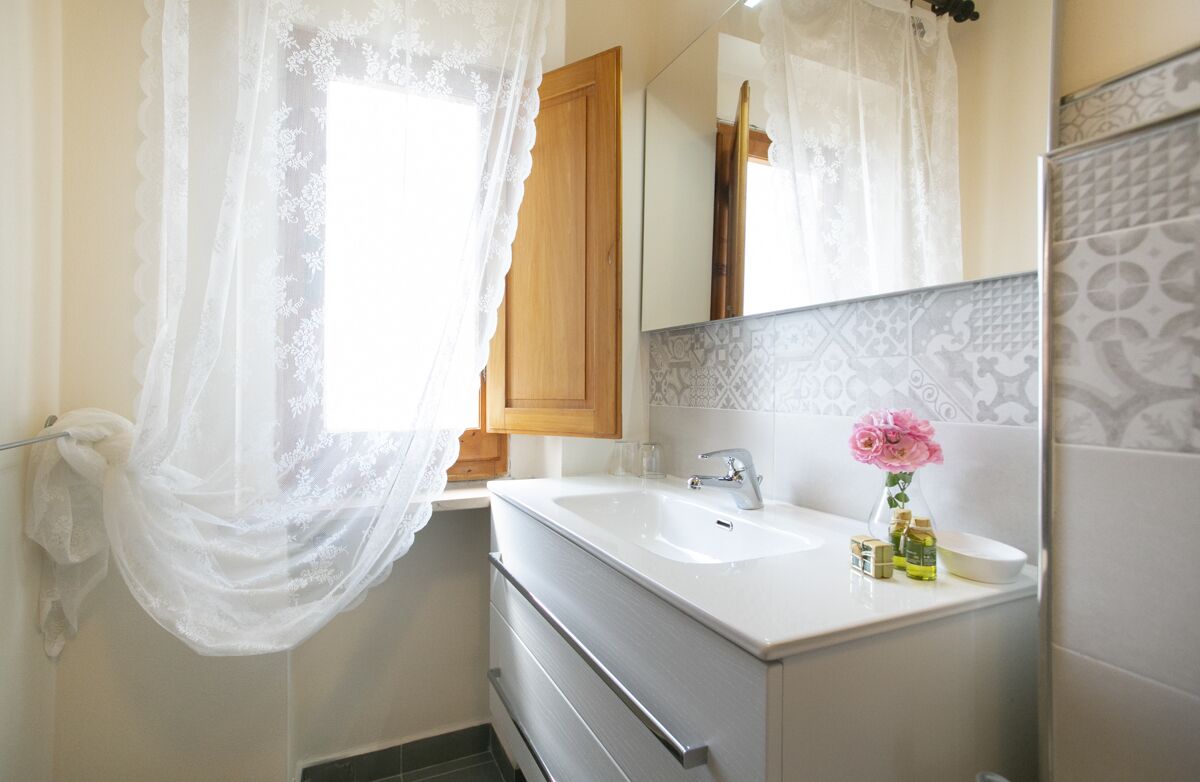 A bathroom with a white sink, a wooden cabinet, a mirror, and a decorative shower curtain.