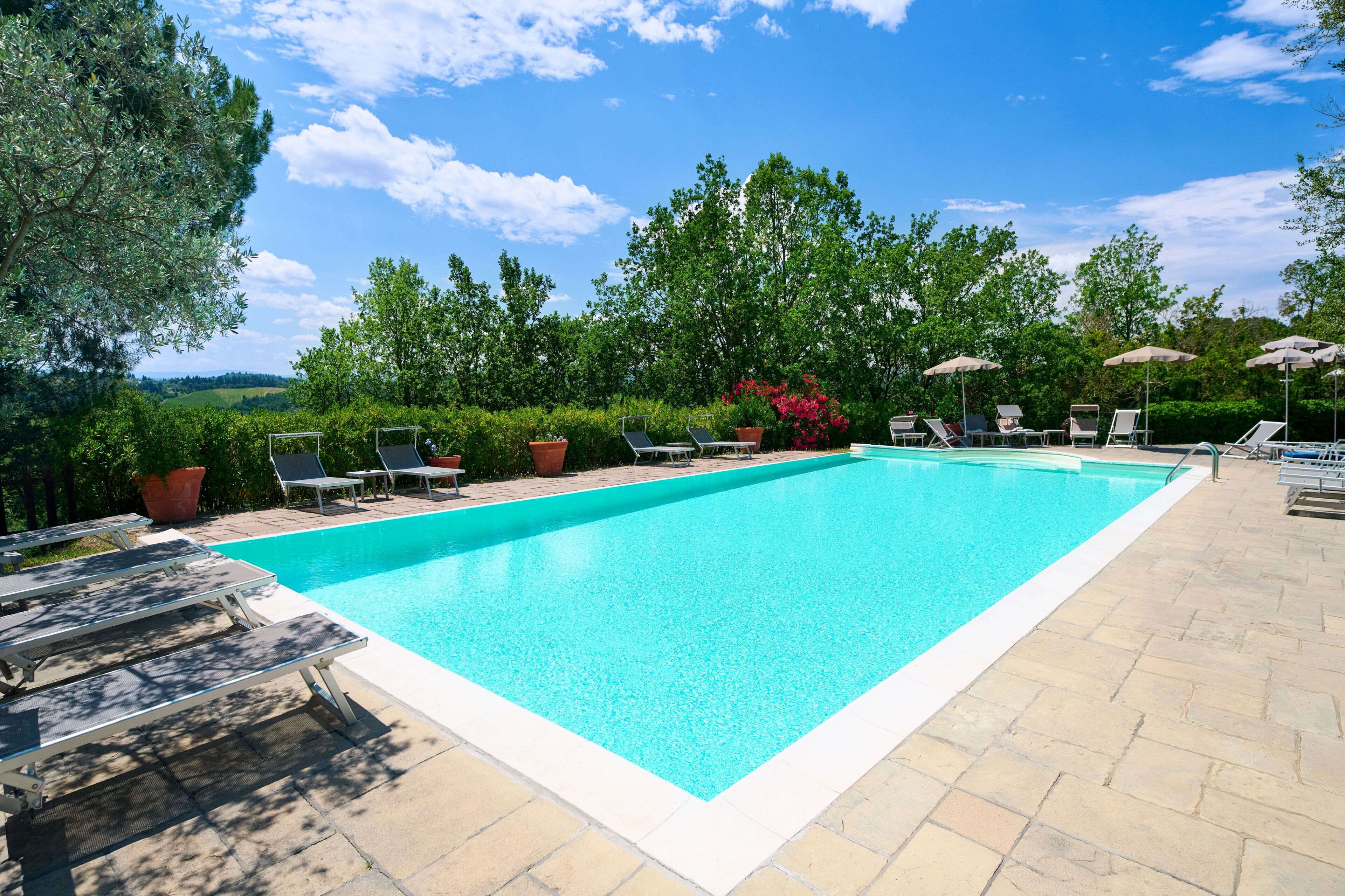 A rectangular swimming pool with a clear blue water surface, surrounded by a paved deck.
