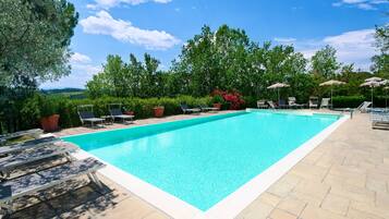 A rectangular swimming pool with a clear blue water surface, surrounded by a paved deck.