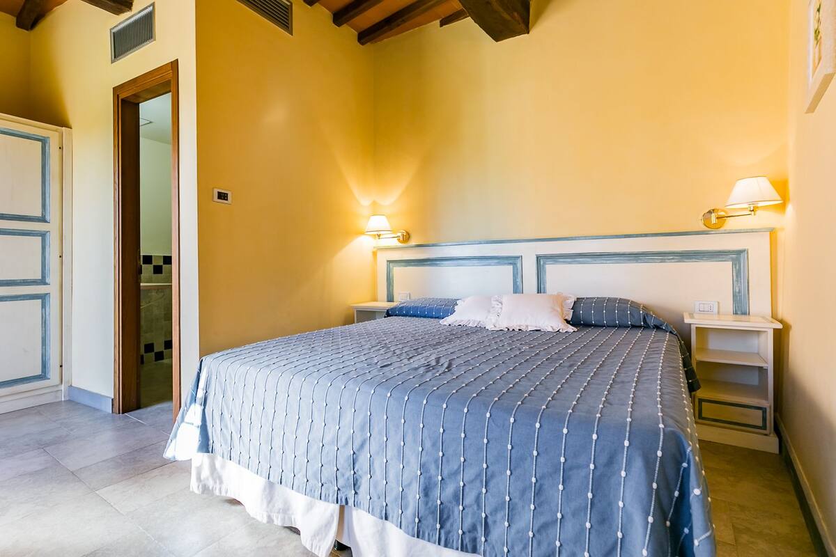 Een slaapkamer met een bed, bedlampen en een nachtkastje.