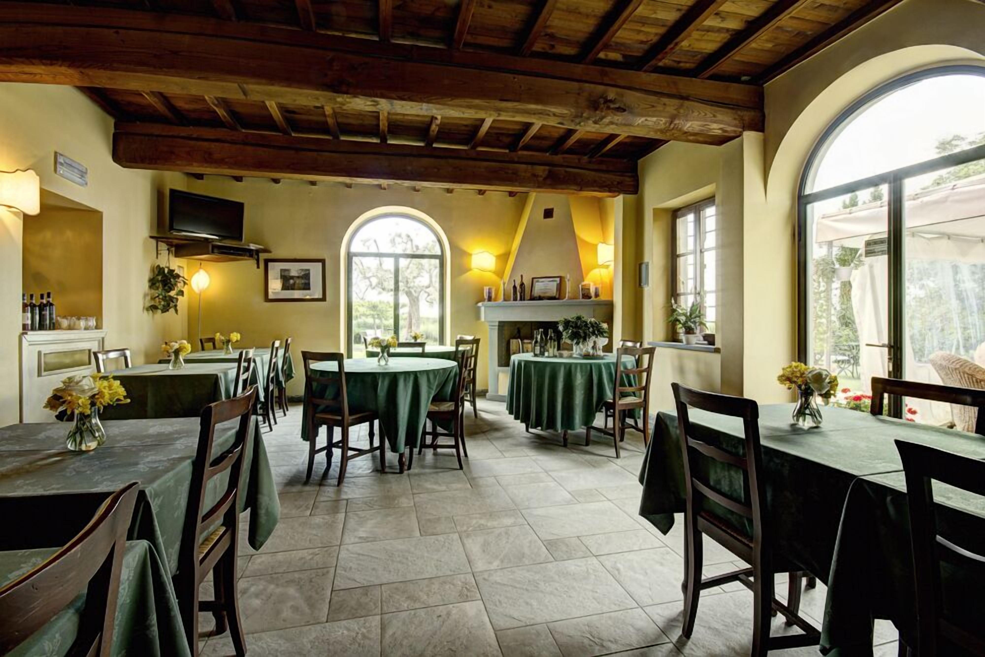A dining area with multiple tables and chairs, a fireplace, and large windows.