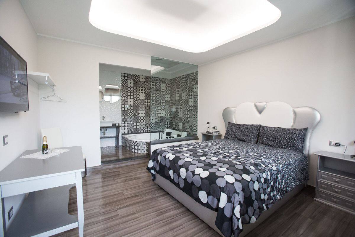 Un dormitorio moderno con una cama grande, un escritorio y un baño visible a través de una puerta abierta.